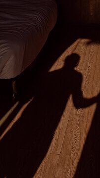 Vertical video. Long Shadow of Woman Walking across Wooden Floor in Bedroom toward Window Opening Curtains Morning Sunlight Casting Dramatic Silhouette Calm Wake Up Lifestyle Scene