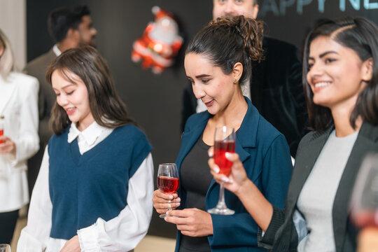 Women social party celebration holding glass of red drink in indoor event with smile and conversation