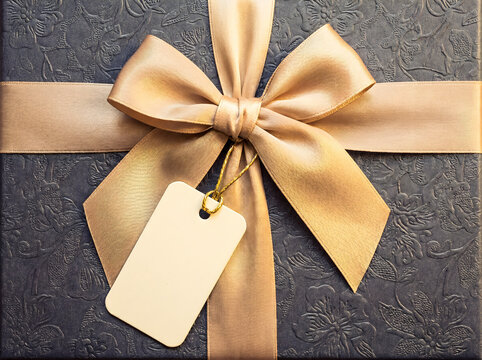 Elegant blue gift box with golden ribbon and blank tag, closeup gift tag mockup