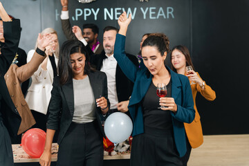 Naklejka premium New year party group of coworkers celebrating with drinks, balloons, and raised hand at festive office event
