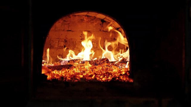 urning fire inside a traditional brick wood oven with glowing embers and baking bread.