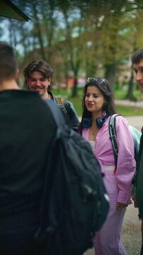 A group of diverse high school friends are seen laughing and socializing happily in an outdoor setting. These young students enjoy their time together, fostering friendship and positive interactions.