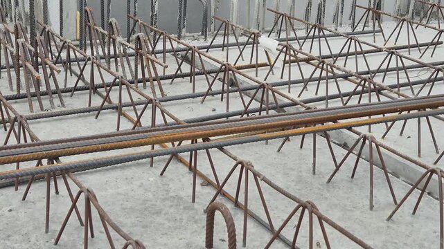 Side view of a construction worker installing joint reinforcement bars on a filigree floor slab system.