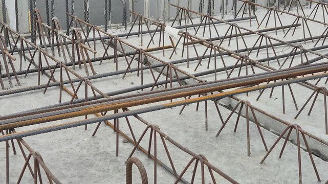 Slow motion shot of a worker's hands placing steel mesh reinforcement over the joints of a precast concrete floor.