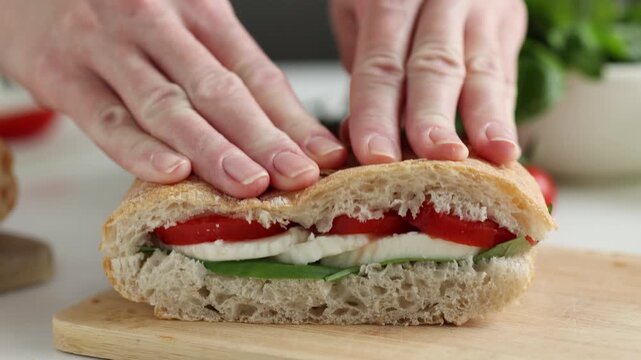 Woman hands cooking healthy panini sandwich with lettuce, mozzarella cheese and tomatoes. Italian style panini sandwich