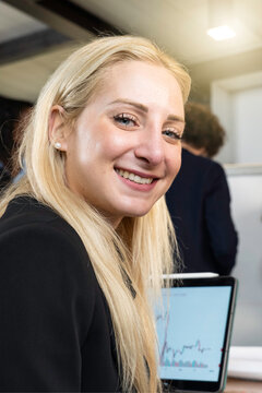 Young blonde caucasian woman looking at camera during business work with tablet at the modern office - Coworking concept - Vertical portrait