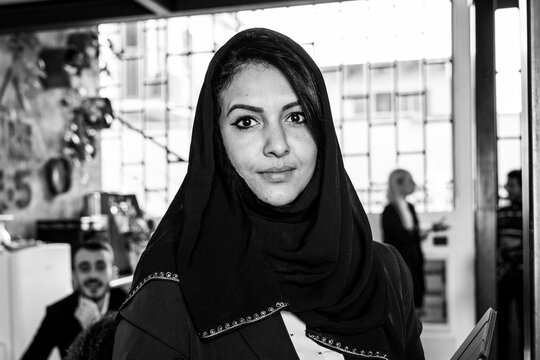 North african businesswoman wearing typical islamic hijab veil and working inside modern office with the multiethnic team - Concept of team achieving goals - Focus on eyes - Black and white editing