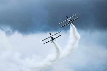 Vintage biplanes with wing walkers performing aerobatics at an air show © PhamHong