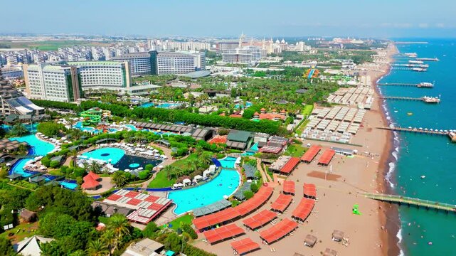 Drone aerial of beachfront resort strip in Antalya, Turkey. Hotels, beach, and turquoise sea in a wide panorama.