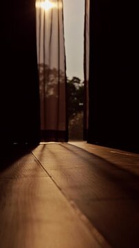 Vertical video. Sliding Curtains Opening to Large Floor to Ceiling Window with Warm Morning Sunlight Casting Long Shadows Across Wooden Floor