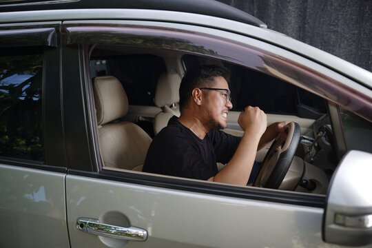 An irritated young man driving a vehicle is expressing his road rage.