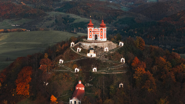 Aerial view of the Kalvaria Banska Stiavnica baroque church complex on a hill surrounded by vibrant autumn foliage and rolling hills in Banska Stiavnica, Banskobystricky kraj, Slovakia.