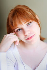 Fototapeta premium Tender indoor portrait of freckled ginger woman with soft focus background, natural beauty and emotional eye contact.