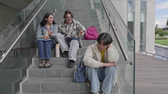 Students bullying their lonely classmate on stairs
