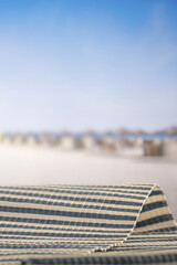 Fototapeta premium Minimal summer composition featuring clean sandy beach with empty copy space for product placement. Rocky coastline meets the sea under bright blue sky, creating natural and scenic atmosphere.