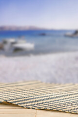 Fototapeta premium Minimal summer composition featuring clean sandy beach with empty copy space for product placement. Rocky coastline meets the sea under bright blue sky, creating natural and scenic atmosphere.
