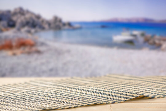 Minimal summer composition featuring clean sandy beach with empty copy space for product placement. Rocky coastline meets the sea under bright blue sky, creating natural and scenic atmosphere.