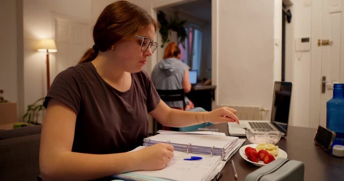 Student's Study Session: A student concentrates intently on her studies, surrounded by textbooks and technology. A glimpse of daily life of her.
