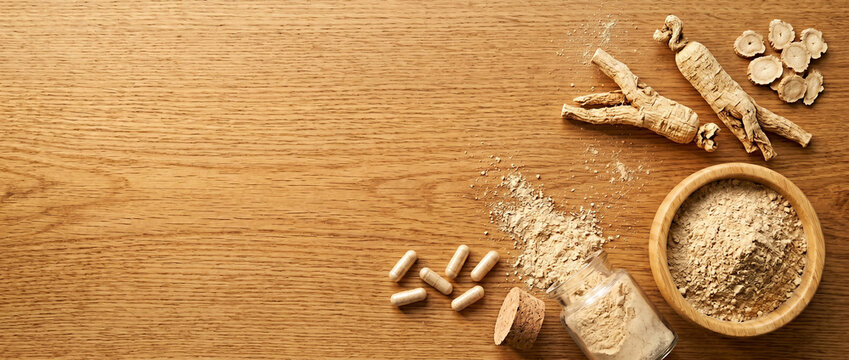 ginseng roots and powder on wooden table with herbal supplement capsules