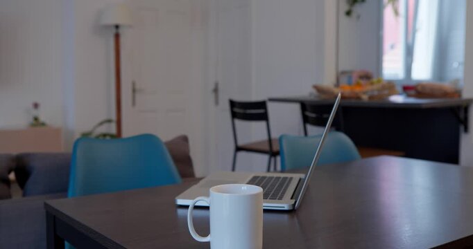 Cozy Workspace: A serene setting with a laptop and a mug of coffee on a table, symbolizing a productive and comforting work-from-home environment.