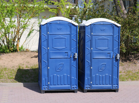Two Blue Portable Toilets Side-by-Side in Public Park &mdash; Photo of Mobile WC Units, Outdoor Event Sanitation, and Public Restroom Infrastructure