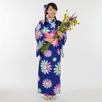 Jeune femme souriante portant un kimono bleu &agrave; fleurs tenant un bouquet