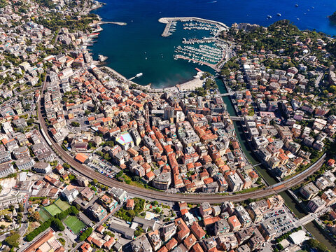 Aerial view of the coastal town with its harbor, dense urban architecture, and railway line under a clear blue sky Rapallo, Liguria, Italy.