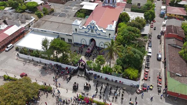 Church in Central America with people celebrating Easter.
Aerial drone footage of Parroquia Inmaculada Concepci&oacute;n de Ataco; Semana Santa Easter procession in Concepci&oacute;n de Ataco, El Salvador.