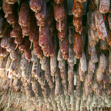 Hanging cured salami and sausages in traditional charcuterie shop