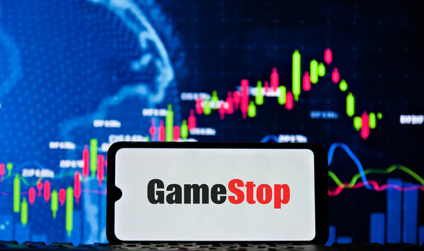 GameStop logo on a smartphone screen with a stock market chart in the background.