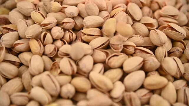 Pistachio nuts pouring and tumbling into pile on tabletop