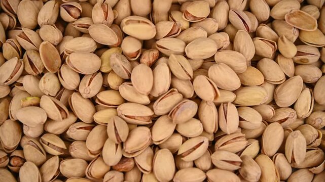 Pistachio nuts pouring and tumbling into pile on tabletop