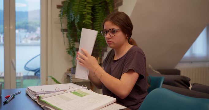 Focused Study: A young person engrossed in their studies, intently reviewing documents in a well-lit interior.