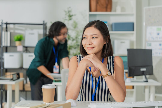 Portrait of smiling young Asian businesswoman in modern office, happy professional female employee working at creative workspace