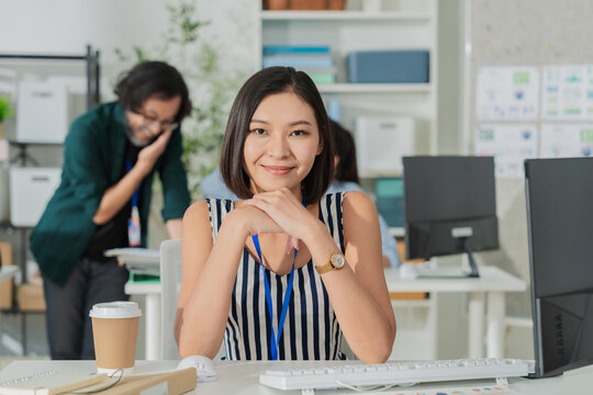 Portrait of smiling young Asian businesswoman in modern office, happy professional female employee working at creative workspace