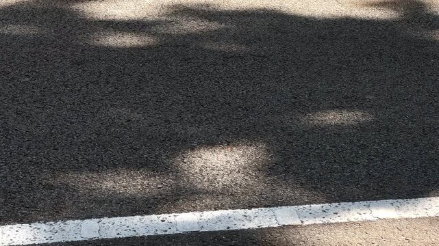 Cars passing over sunlit asphalt with motion blur and ground level perspective