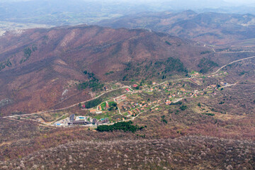 Fototapeta premium High angle view of a remote mountain village and resort nestled among the hills and forests, with roads winding through the valley