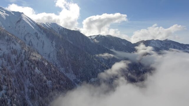 Aerial clouds drifting above snowy mountain ranges and deep alpine valleys in winter light. Layered vapor, icy summits, dramatic heights, cold wilderness, panoramic highland scenery.