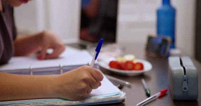 Focus on the Task at Hand: An individual is deeply engrossed in writing, surrounded by study materials, symbolizing focused study and dedication.