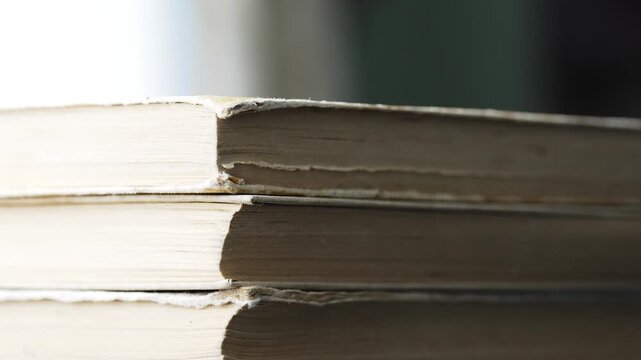 Close up of stacking a pile of old vintage books side view of yellowed paper edges and pages
