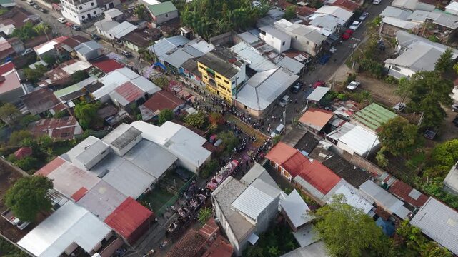 Aerial footage of a Semana Santa Easter procession in Concepci&oacute;n de Ataco, El Salvador. Colourful alfombras de aserr&iacute;n made from dyed sawdust and flowers create intricate street patterns.