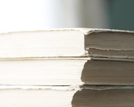 Taking away old vintage books one by one from a stack side view of yellowed paper edges and pages
