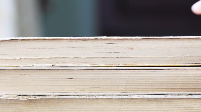 Close up of stacking a pile of old vintage books side view of yellowed paper edges and pages
