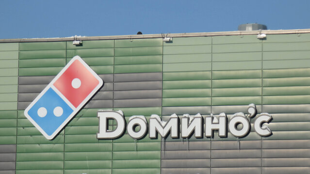 Sign for Domino's Pizza on a building during bright daylight hours, showing logo and name clearly on display