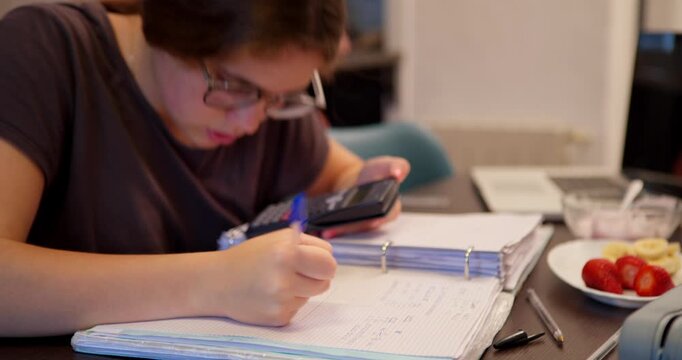 Concentration & Study: A young person, immersed in a study session, meticulously takes notes while simultaneously checking their phone and surrounded by study materials and snack. 