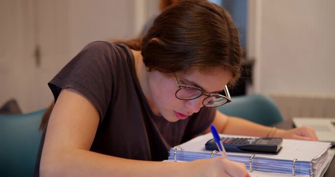 Focused Study: A young student diligently works on her studies, immersed in concentration as she meticulously takes notes and engages in academic work.