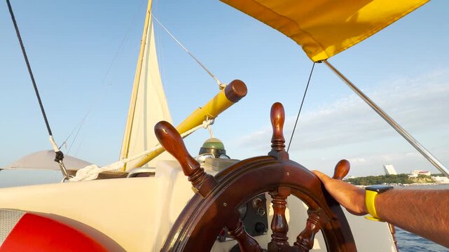 Captain hands wooden steering wheel. Skipper helm sailing yacht. Sea voyage, adventure. View city from yacht. Sailing. Seaside recreation. Sailing vacation. Free man traveling under sail on ship.