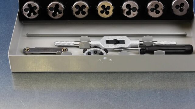 A set of tools for threading in a metal case.