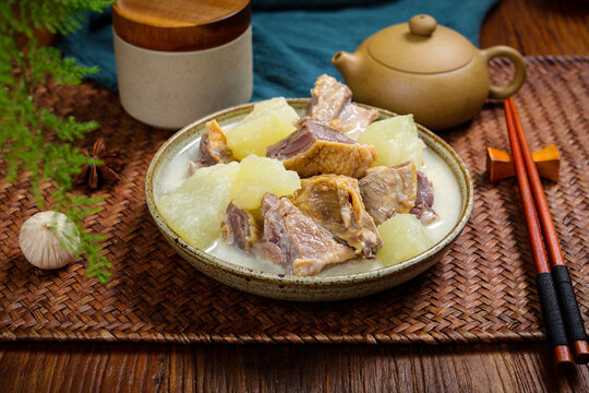 Winter melon and duck soup with teapot and chopsticks on rustic table