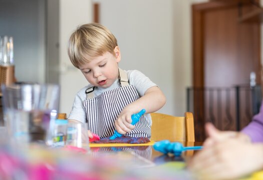 Blond boy sculpts from plasticine at home at the table. The idea and concept of the school, home education and developmental activities.